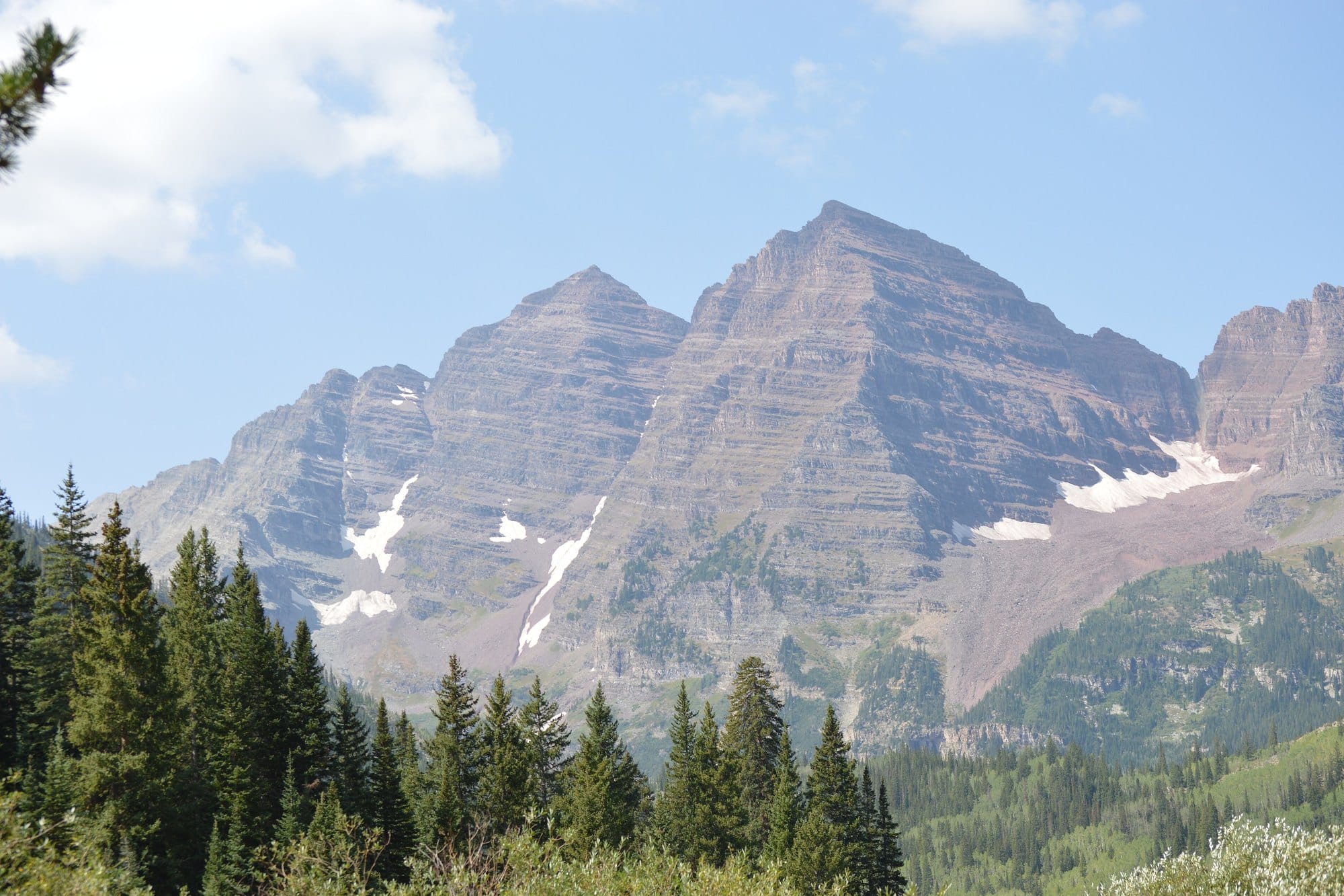 The Maroon Bells rising above pine trees on the trail to Crater Lake