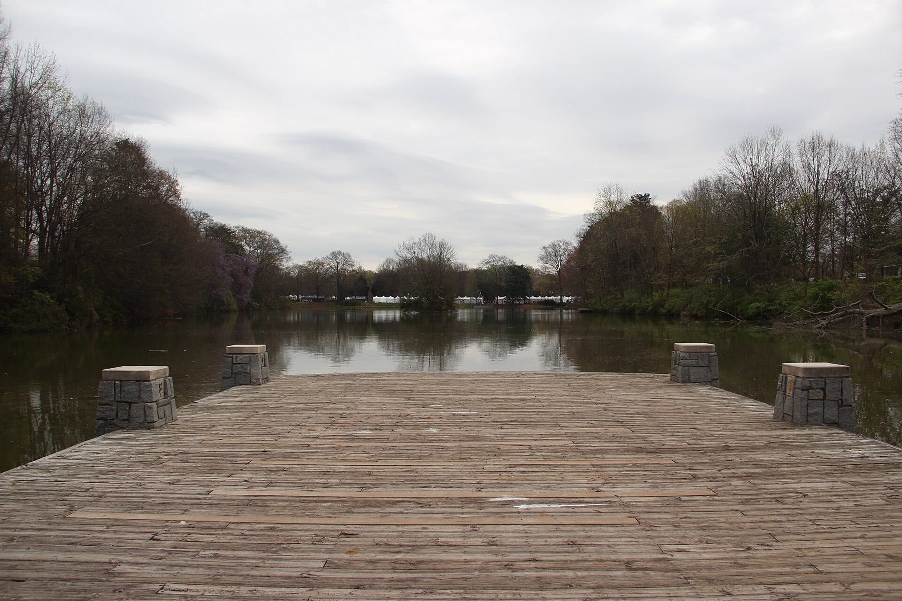 A wooden pier looking out over Lake Clara Meer in Piedmont Park, with trees on both banks