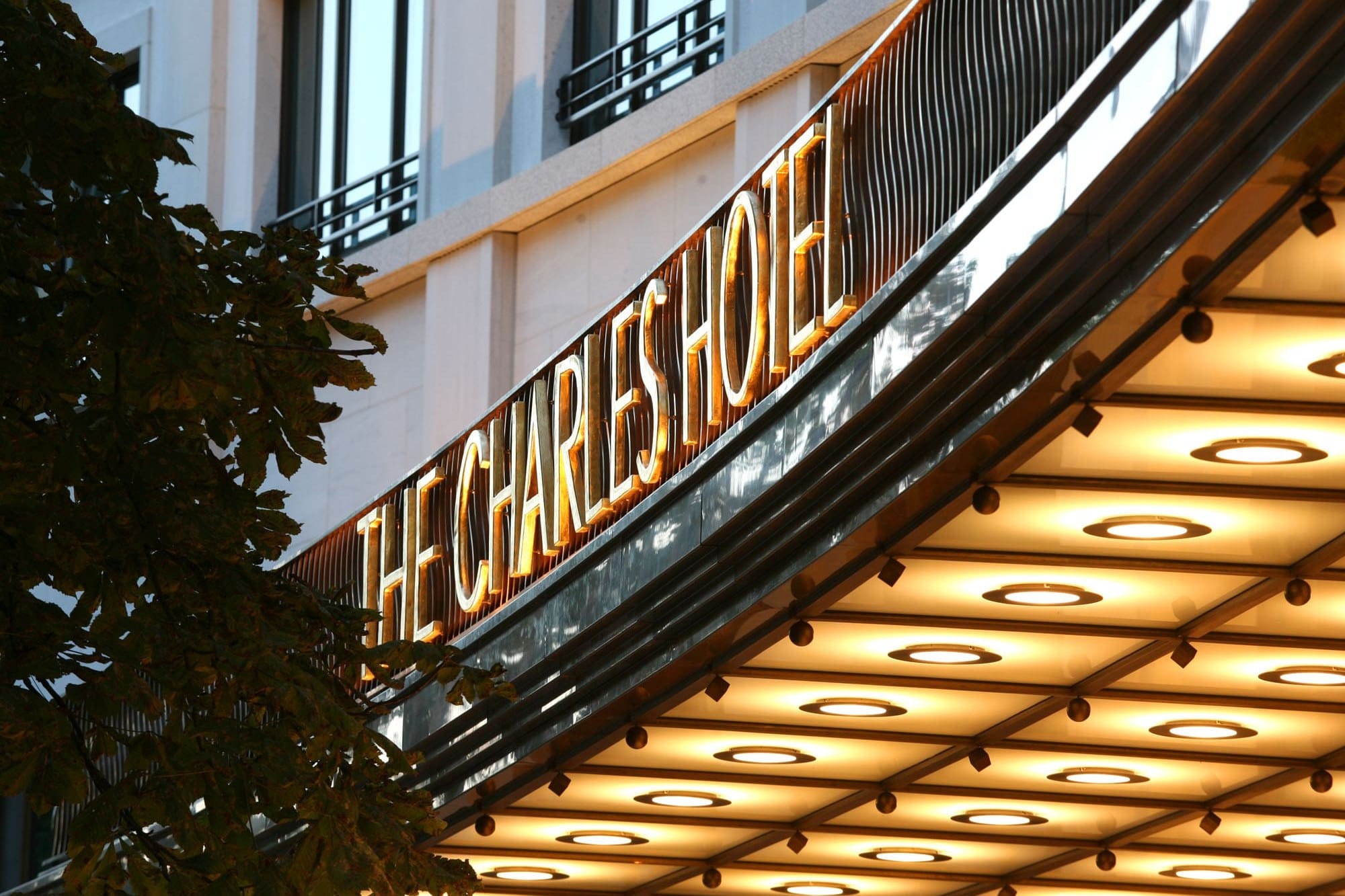 The gilded The Charles Hotel lettering above the illuminated entrance canopy on Sophienstrasse