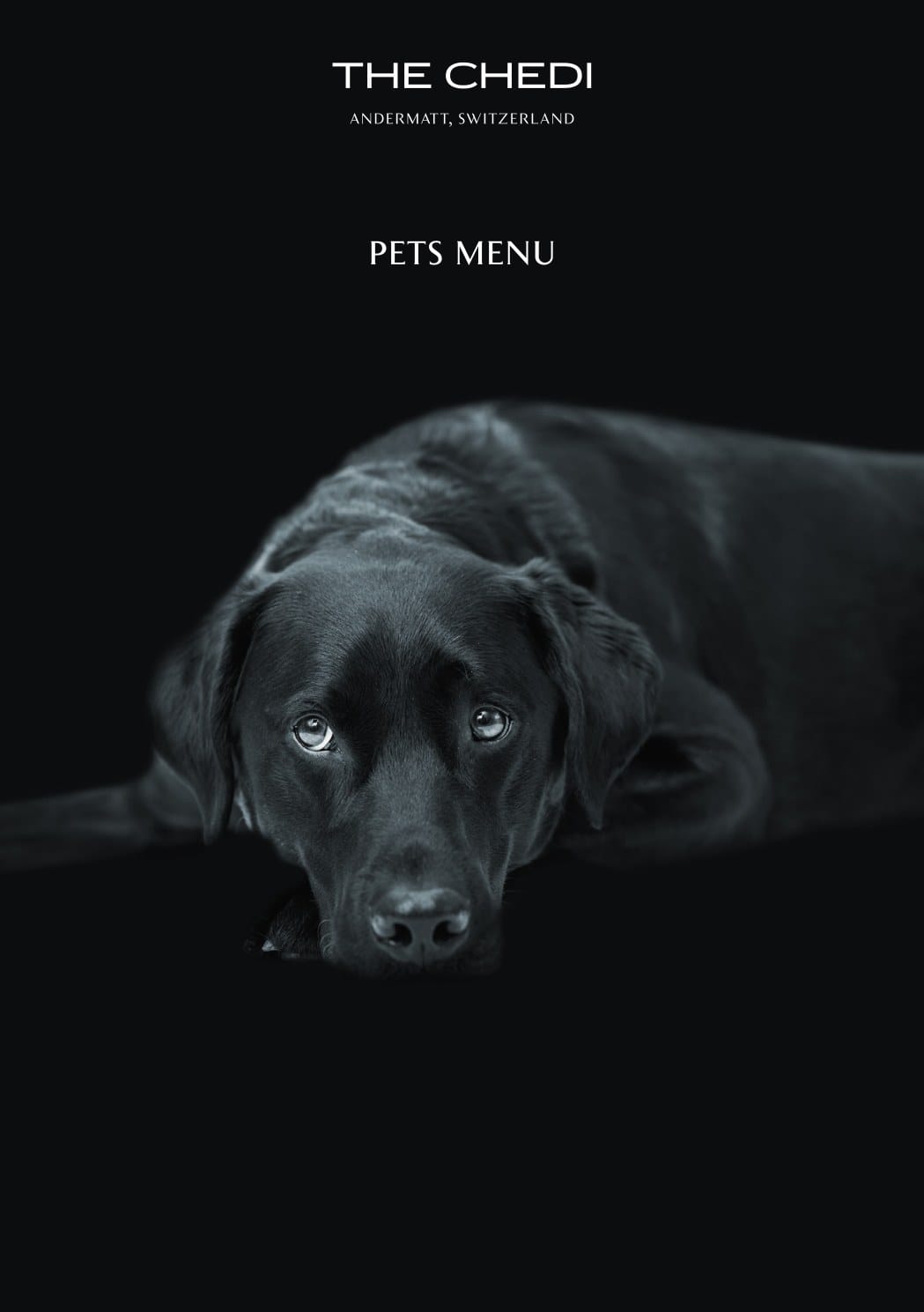 The Chedi Andermatt pets menu cover, a black labrador lying down against a black background