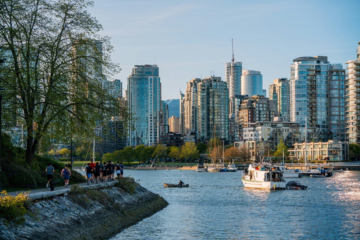 Runners on Vancouver's seawall beside False Creek, with the city's towers behind