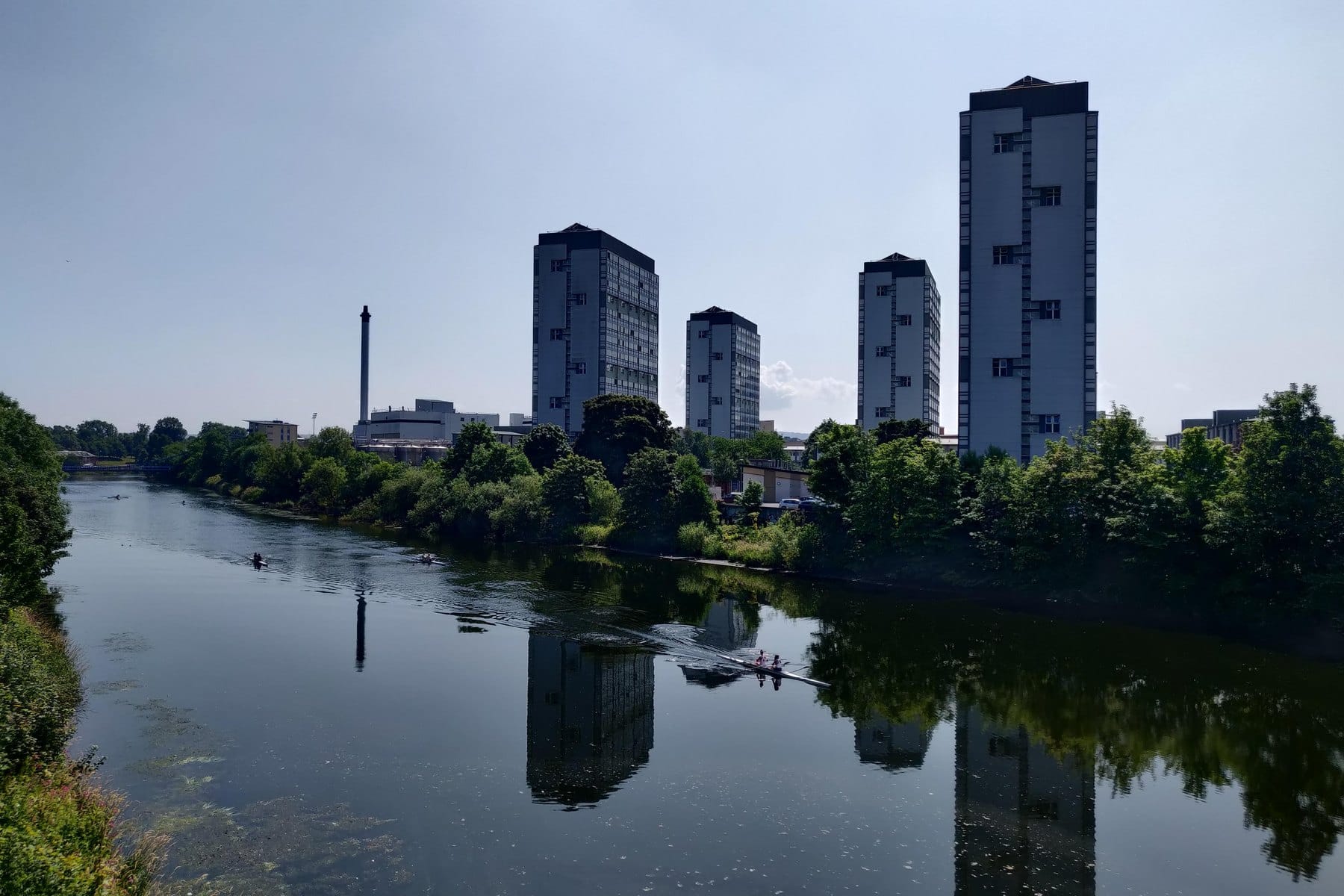 Rowers on a still stretch of the River Clyde beside Glasgow Green on a sunny day