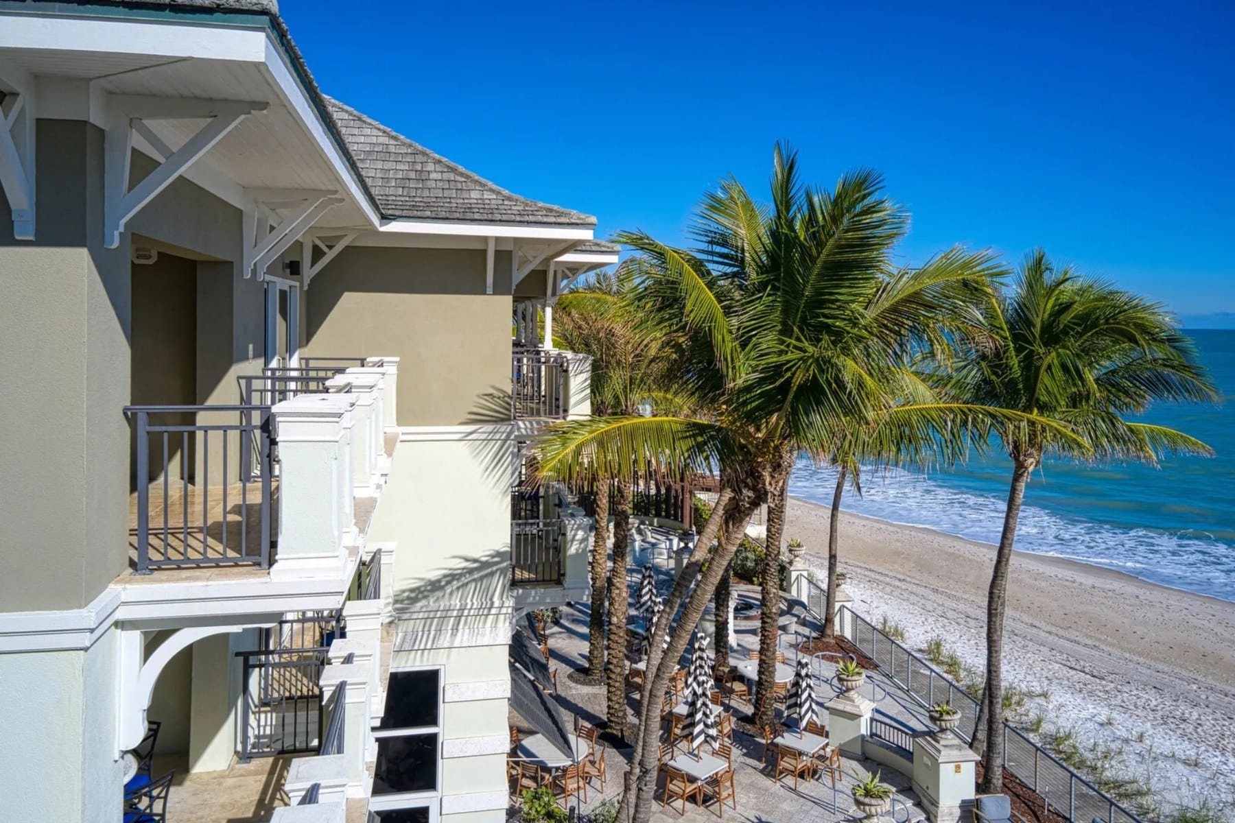 Balconies of the Kimpton Vero Beach above palms, the pool terrace and the beach