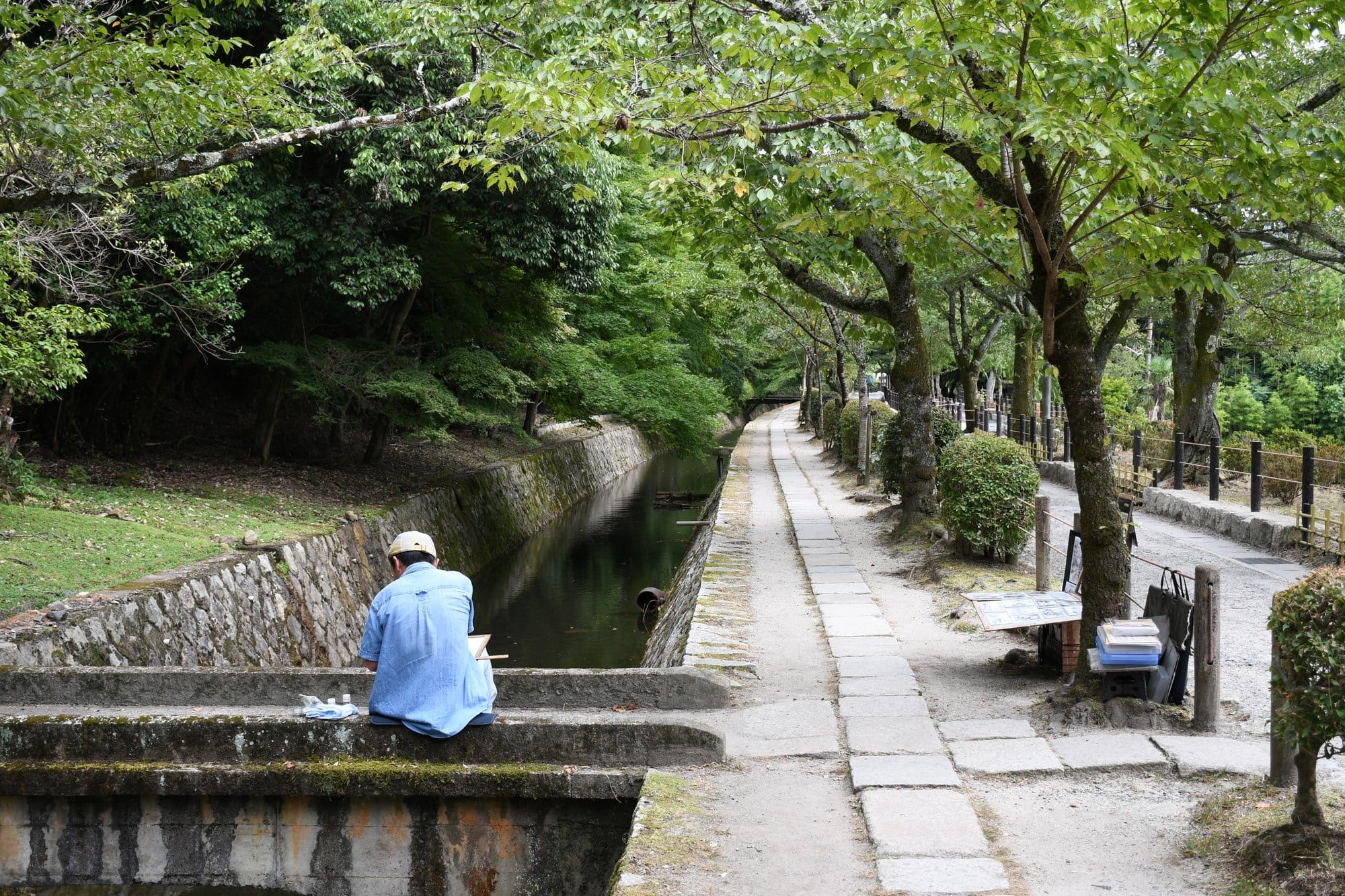 The stone paved Philosopher's Path in Kyoto running beside a narrow canal under green cherry trees
