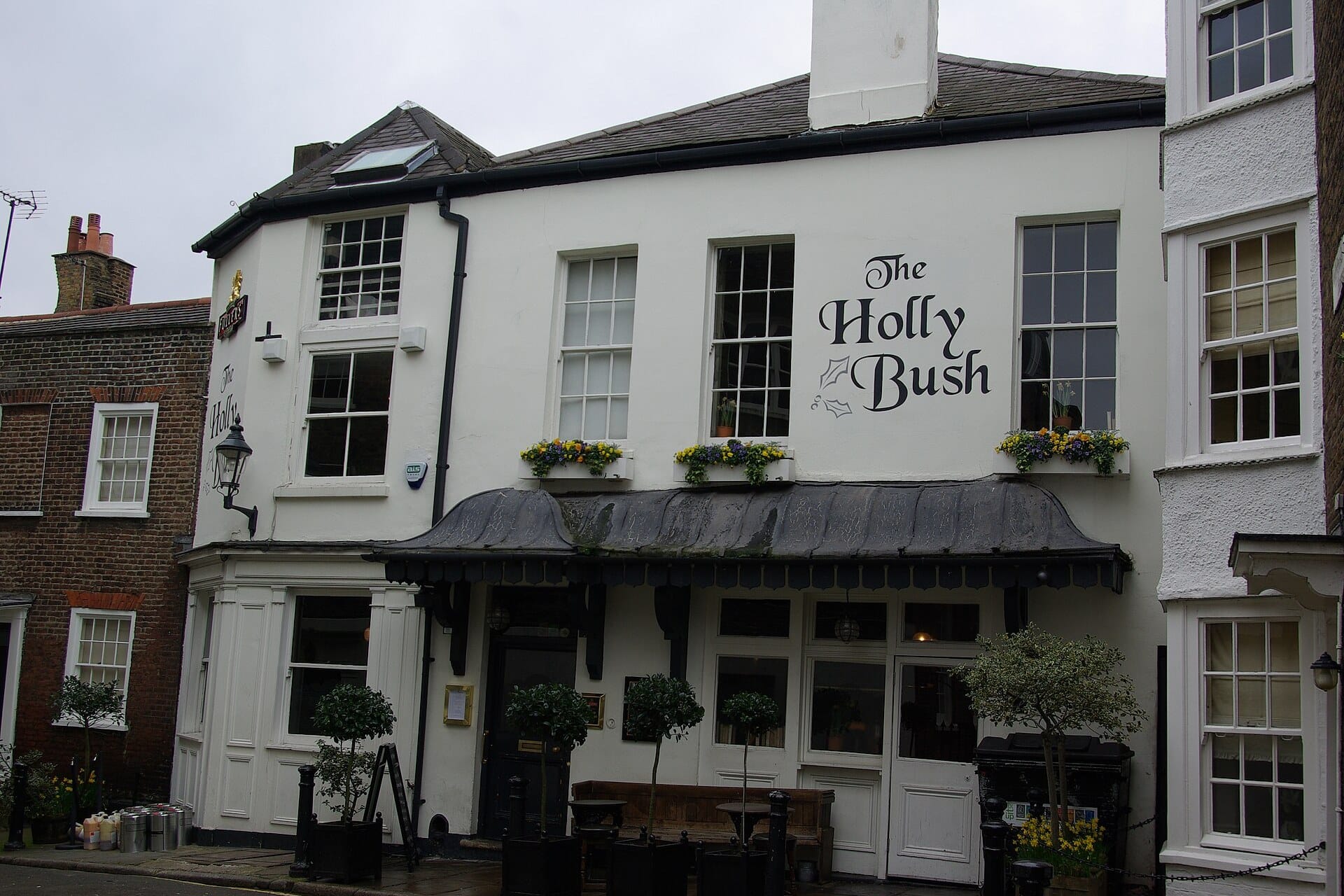 The white painted front of The Holly Bush pub in Hampstead with window boxes and a canopy
