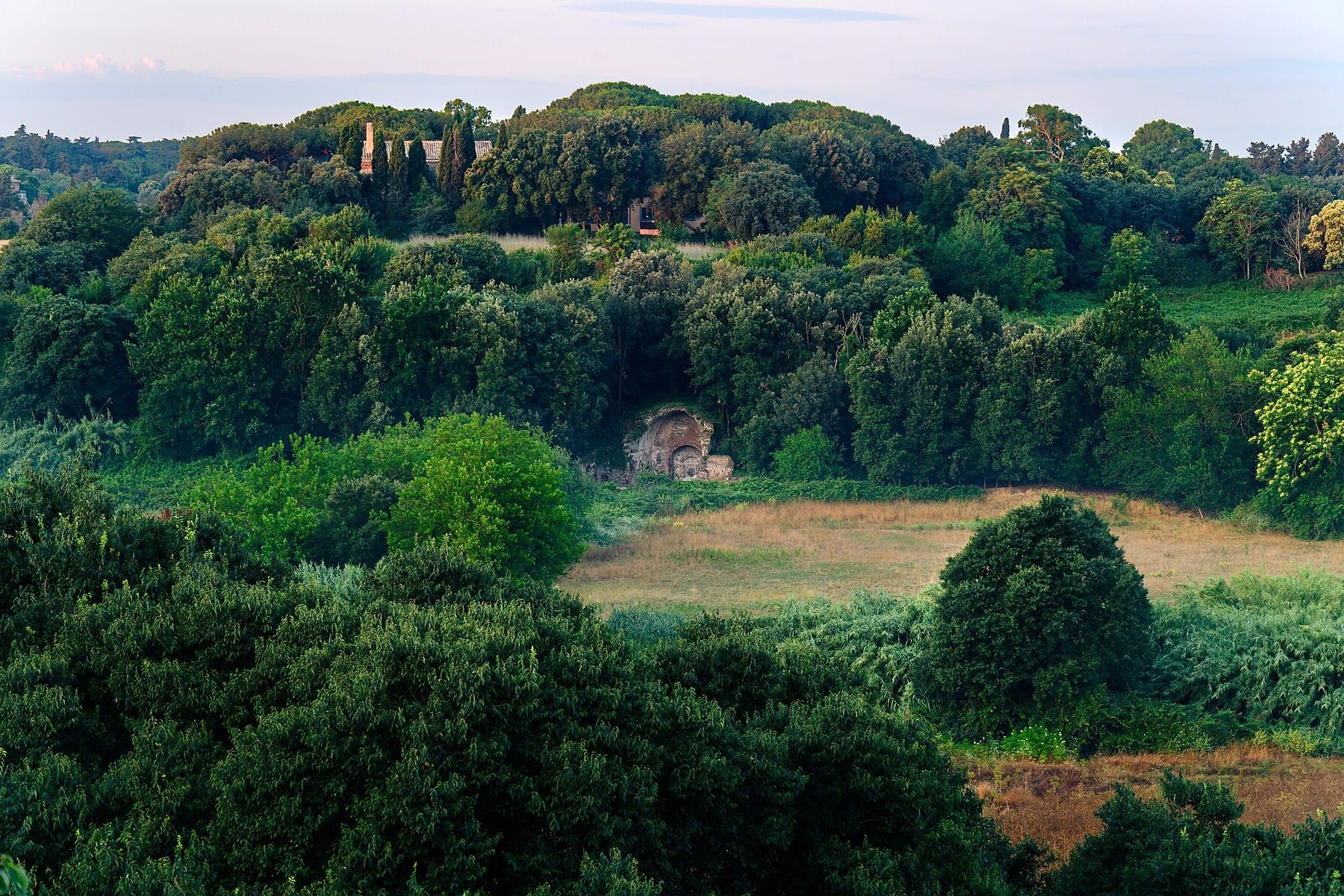 Woods and open meadow in the Valle della Caffarella, Rome, with an ancient nymphaeum among the trees