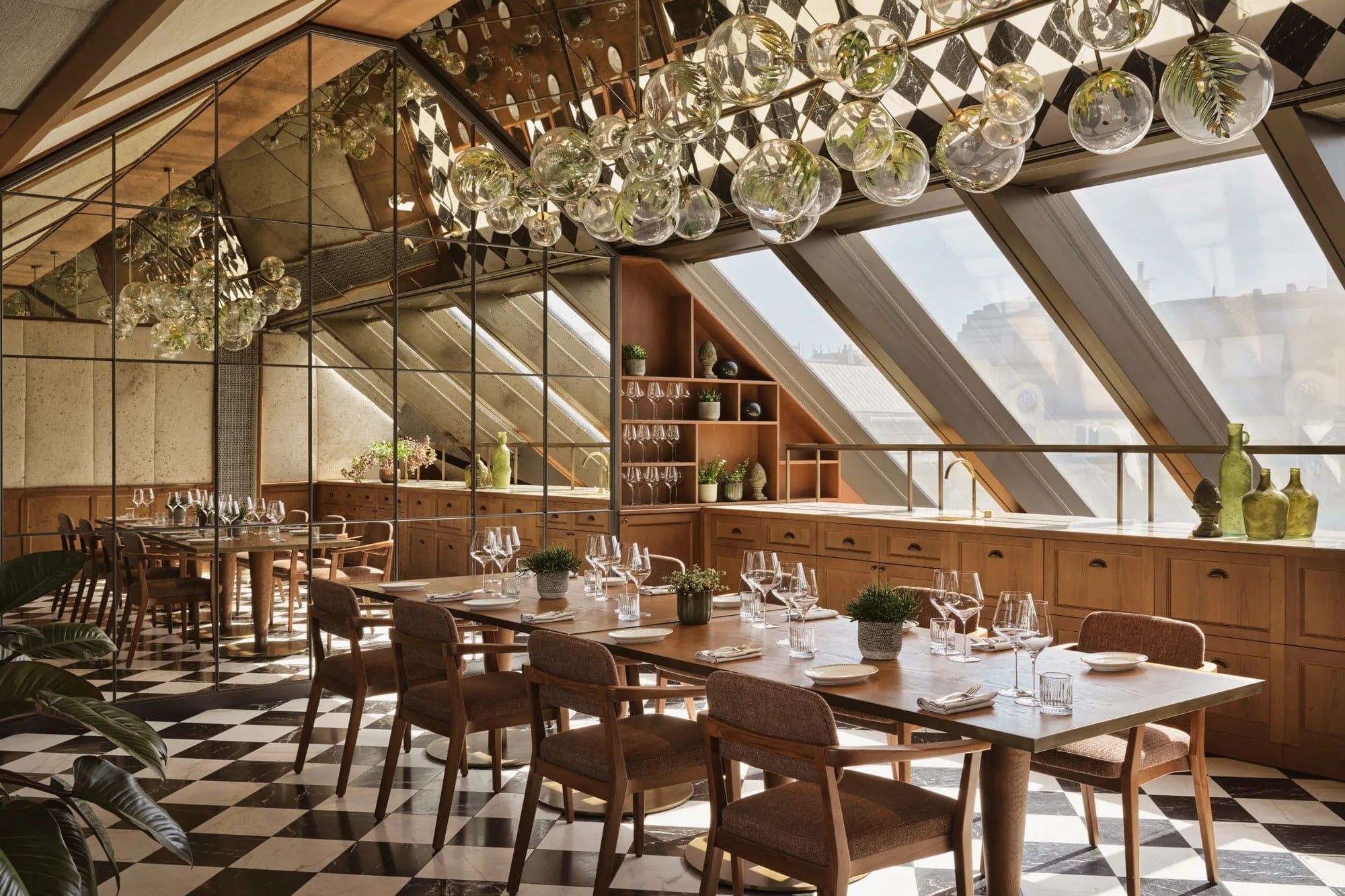 A dining room under a sloping glass roof at Rosewood Vienna, with a chequered floor and glass globe lights