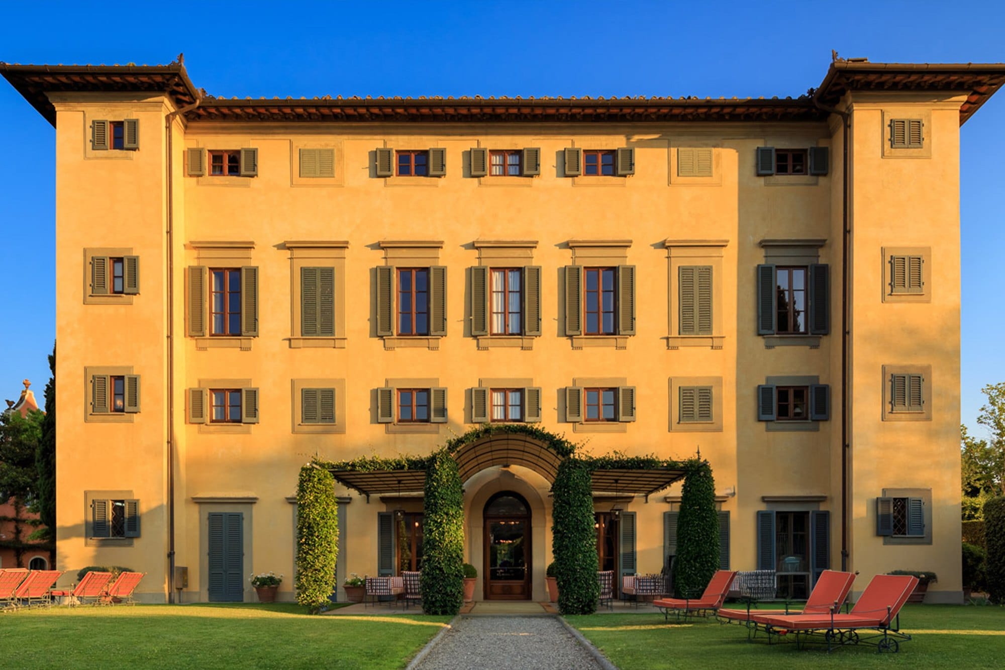 The ochre facade of Villa Nobile at Villa La Massa with its corner towers and lawn