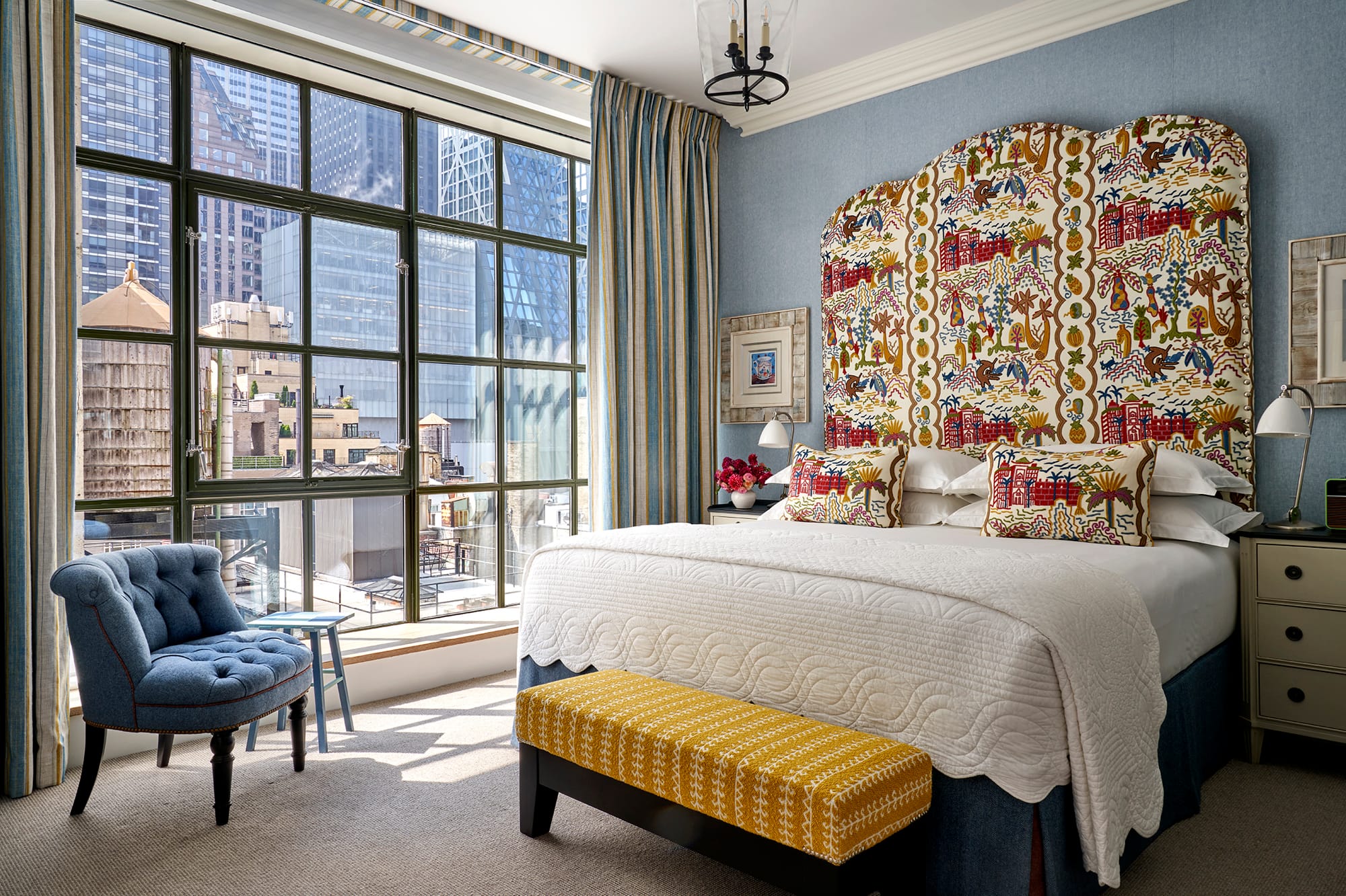 A Whitby suite bedroom with a patterned headboard and floor to ceiling windows over Midtown