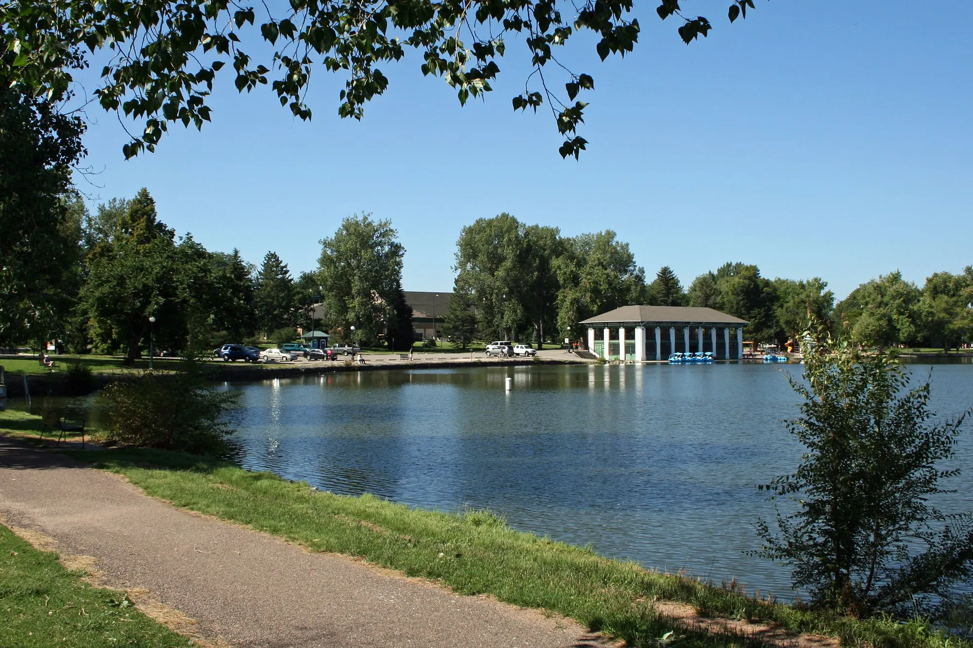 A path beside the lake and boathouse in Washington Park, Denver, under summer trees