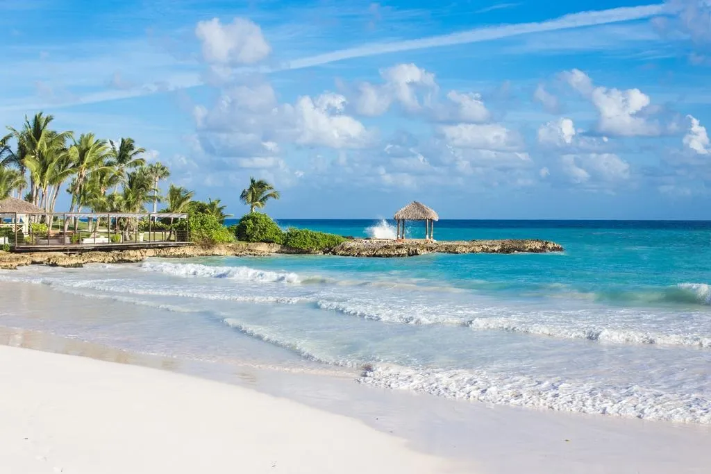 White sand beach, turquoise sea and a thatched shelter on the coral rocks at Eden Roc Cap Cana