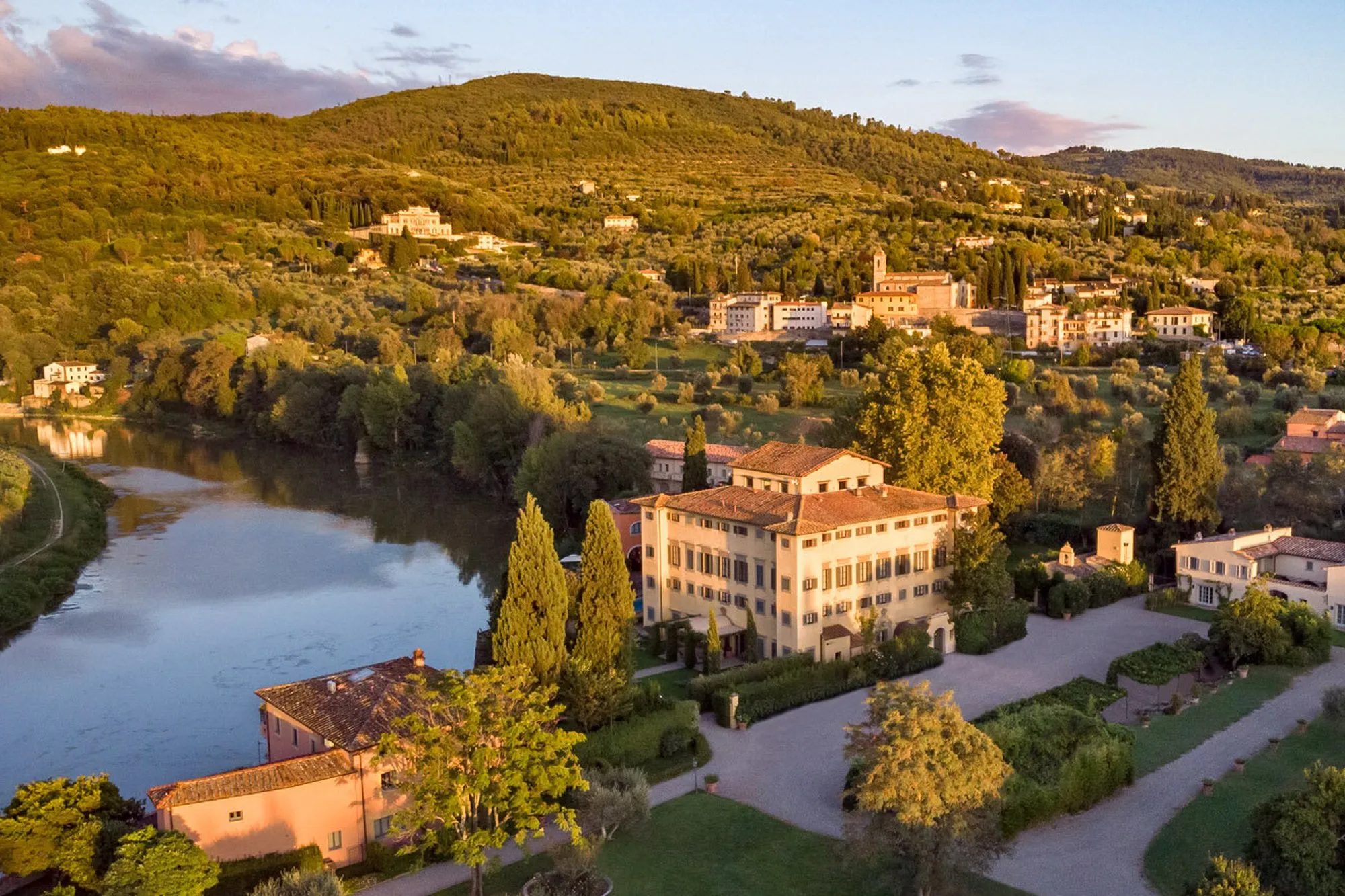 Aerial view of Villa La Massa and its gardens on a bend of the River Arno, with the Tuscan hills behind