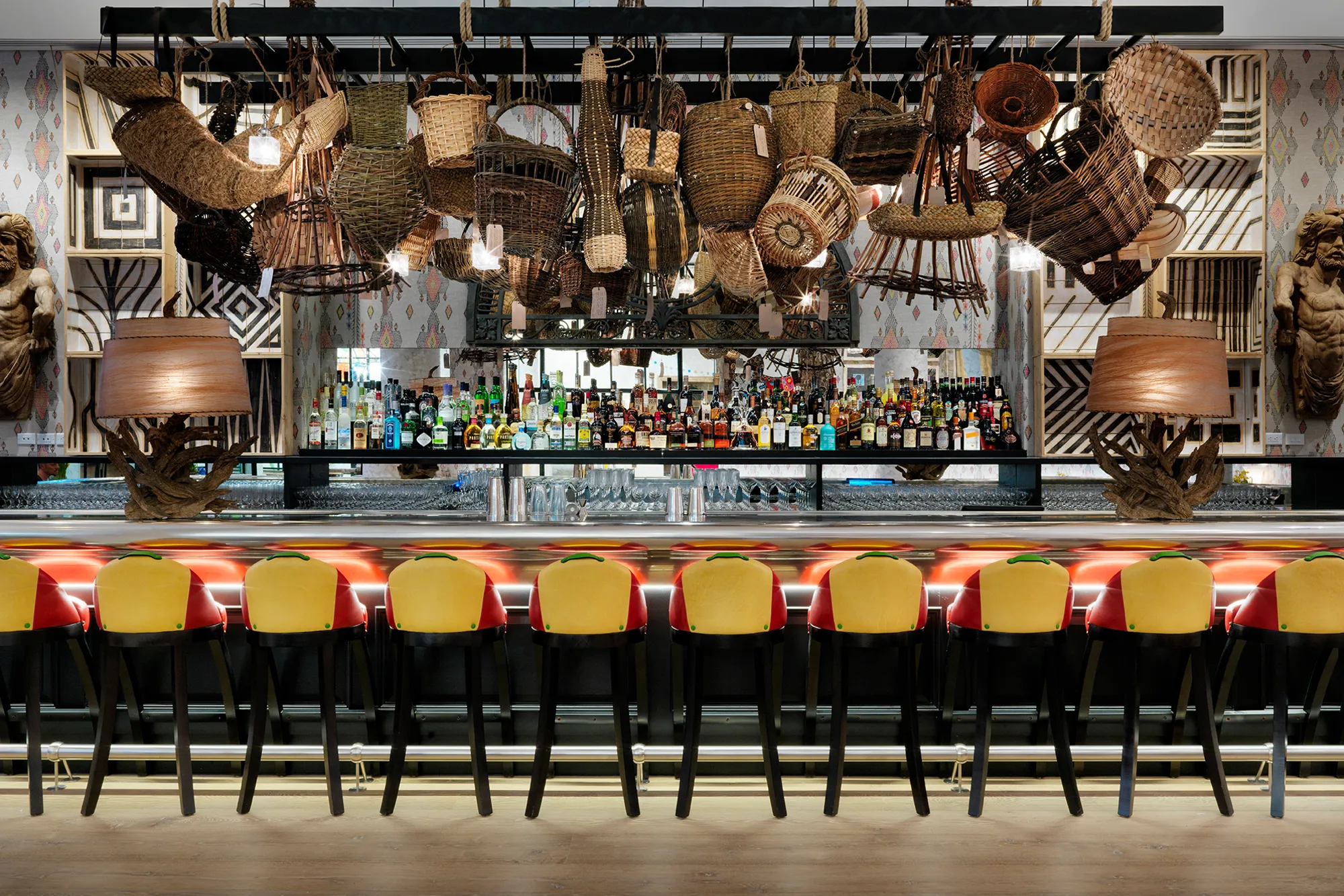 The Whitby Bar, with woven baskets hung above a long pewter topped bar and yellow bar stools