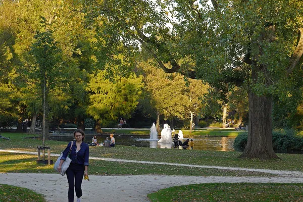 A path through the Westerpark in Amsterdam in autumn, with the pond and fountain beyond