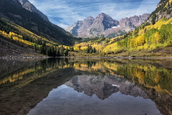 Maroon Lake reflecting the Maroon Bells, with aspen trees turned yellow on the slopes either side