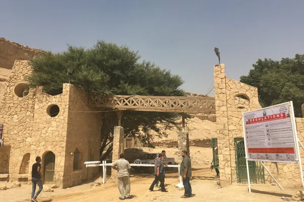 The stone gateway of Wadi Degla Protectorate on the edge of Maadi, Cairo, with a large acacia tree behind and a regulations board beside it