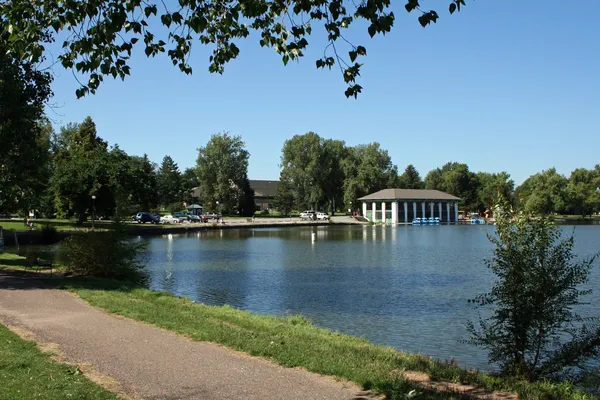 A path beside the lake and boathouse in Washington Park, Denver, under summer trees