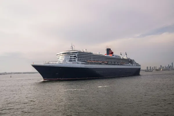 Queen Mary 2 sailing through New York Harbor with Manhattan behind